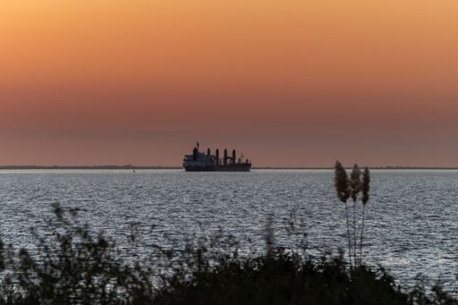 A beautiful soft orange sunset over the sea with a cargo ship
