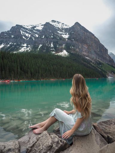 A girl at beautiful Lake Louise Chateau in front of green glacier lake and mountain view in Canada