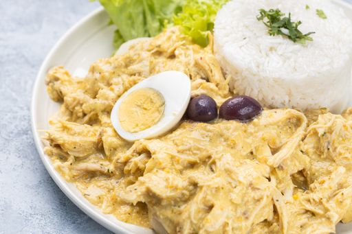 A closeup shot of a dish with chicken salad, rice and half of an egg