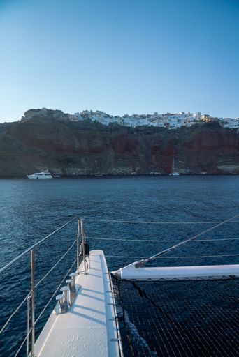 A vertical shot of Santorini on a mountain from a catamaran in the ocean