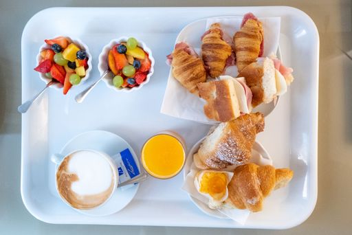 A top view of fruits, croissants, coffee, and juice on a breakfast tray
