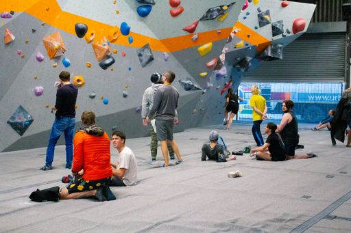 A group of rock climbers hanging in front of the climbing wall with colorful slopers in the gym