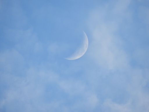 A beautiful view of a quarter moon in a blue sky with clouds