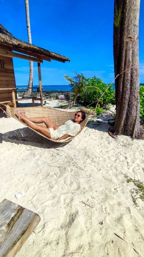 A beautiful South Asian female lying in a hammock on a sandy beach