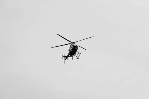 A low angle shot of a helicopter flying in a clear white sky