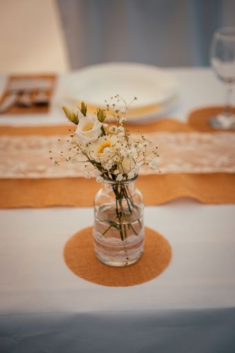 A white rose bouquet decoration in a glass jar, vertical shot