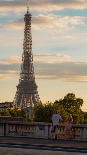 A vertical shot of the Eiffel Tower with tourists looking at it