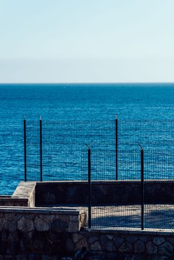 A vertical shot of sea with fence in the foreground
