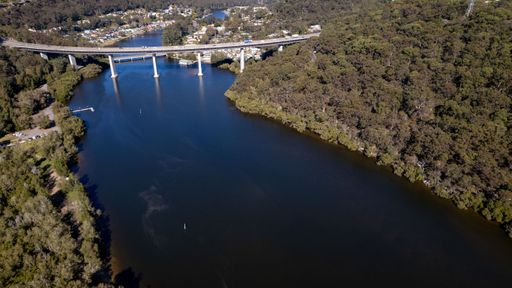 Aerial view of Woronora River surrounded by lush greenery and Woronora Bridge in Sutherland suburb South Sydney, NSW, Australia