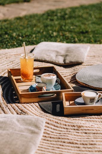 A vertical shot of wooden breakfast boards with a cappuccino and a glass of lemonade
