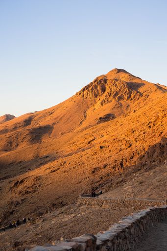 A rocky hill with with sunlight under blue clear sky at sunset, vertical shot