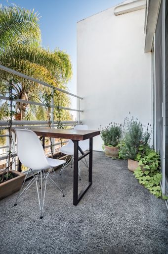 The vertical view of a fenced balcony with chairs, table, and plants