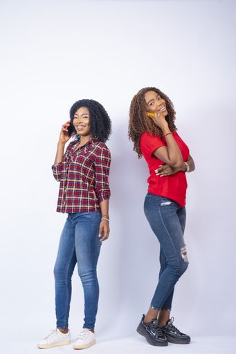 A vertical shot of young African females making phone calls standing back to back