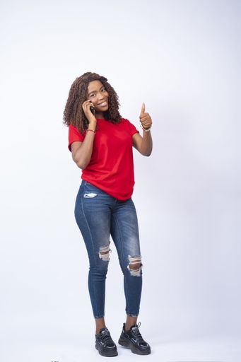 A vertical shot of a young black female making a phone call giving thumbs up - advertisement concept