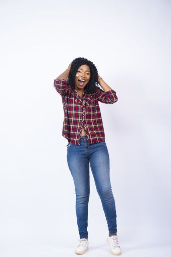 A vertical shot of an excited black female holding her head