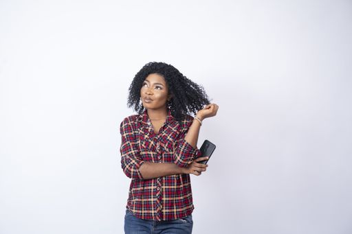 A shot of a young back female holding her phone and thinking about something