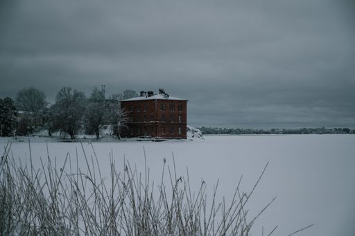 The frozen ocean on a cloudy winter day with a red building in the horizon