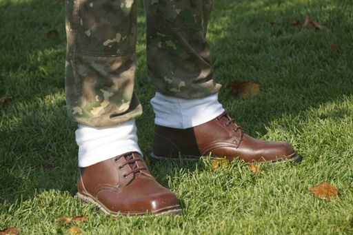 A closeup shot of male feet wearing brown leather shoes and camouflage pants