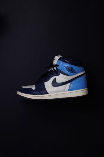A  vertical shot of a Sneaker Nike White Air Jordan 1 Obsidian isolated on the black background