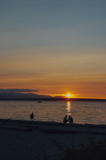 A scenic vertical shot of people at the beautiful beach in Seattle during a mesmerizing sunset