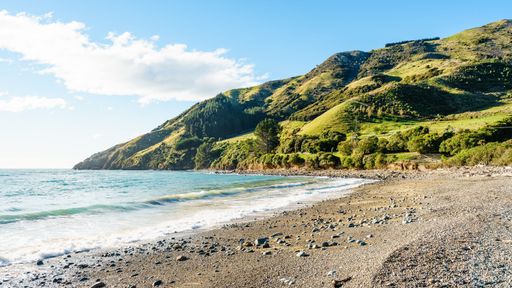 An aerial view of water waves breaking beach surrounded by greenery mountains