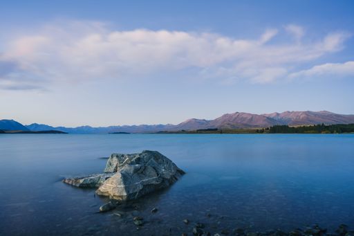 An aerial view of Tekapo lake surrounded by trees and mountains