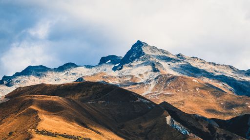 An aerial view of snow covered Cook mountain landscape under blue bright sky