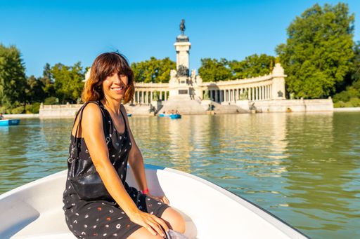A smiling Caucasian female tourist in the boat of the Estanque Grande de El Retiro in Madrid, Spain