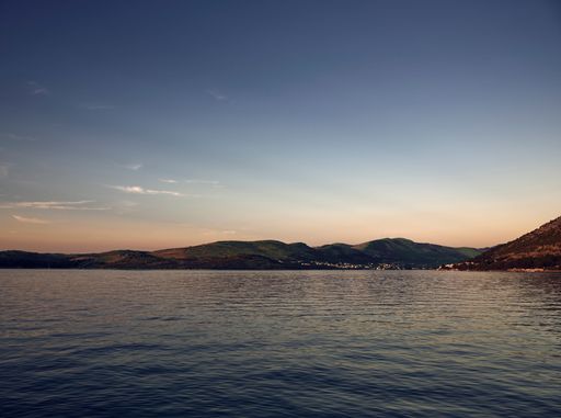 An aerial view of Adriatic  sea surrounded by hills during sunset