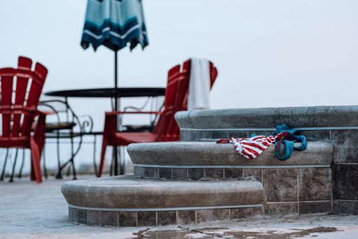 The stone steps on the side of an outdoor pool with wet swimsuits