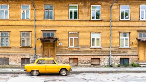 Tallinn in Estonia, wooden yellow house, typical facades in Kalamaja, with a yellow car in the street