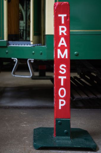 A vertical shot of a sign for "tram stop" on a red post