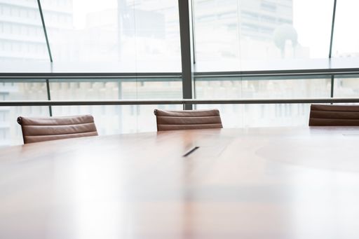An interior of an office with brown leather chairs and a wooden table with panoramic windows