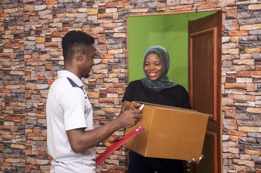 A satisfied African female receiving a parcel from the courier