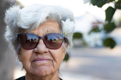 A closeup of portrait of Brazilian senior woman with white hair and sunglasses looking at the camera