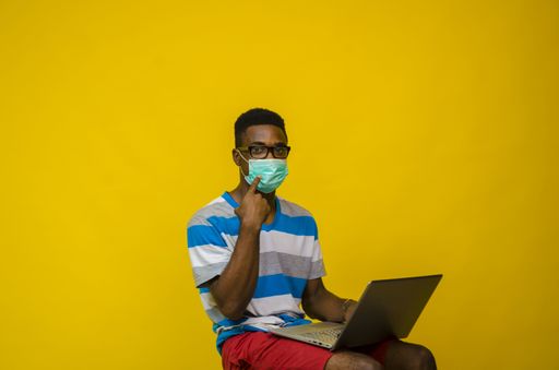 A young African man wearing a face mask isolated over a yellow background