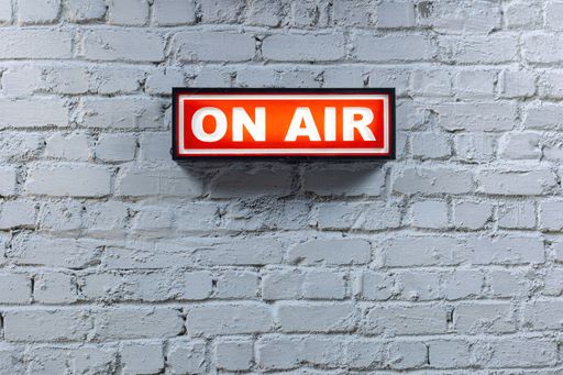 a red on air sign against a white brick wall