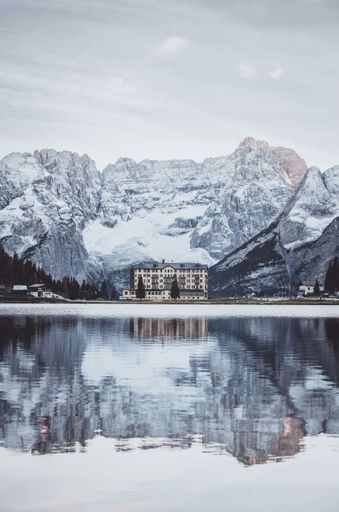 A vertical shot of the Grand Hotel near Misurina Lake with snow-covered mountains in the background