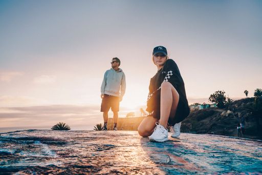 The low-angle view of a young couple on the rock top at sunrise in California