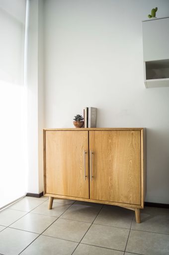 A beautiful shot of a luxurious wooden storage buffet cabinet with the white wall in the background