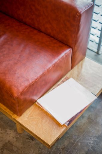 A high-angle shot of a sofa with natural leather seat and copybooks on the wooden part