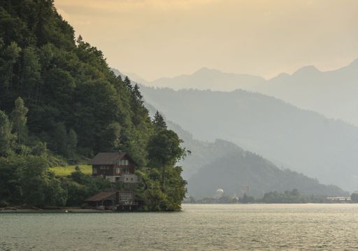 A vertical shot of a house at the shore of Lake Brienz with beautiful mountains in the background, Iseltwald village, Canton of Bern, Switzerland