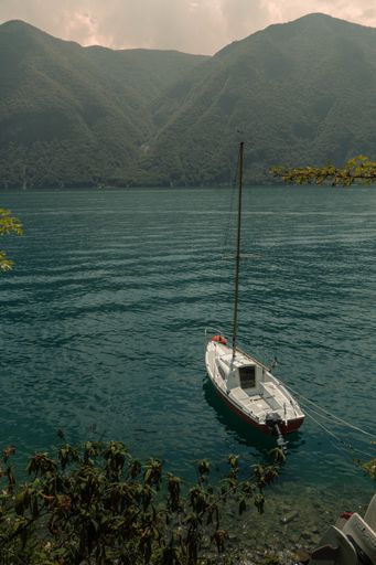 A vertical shot of a boat floating on the Lugano Lake surface in Switzerland