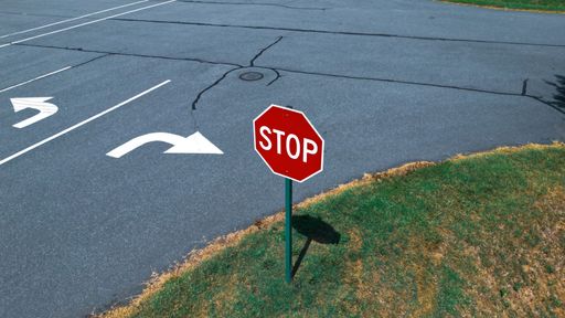 An aerial shot of a red Stop sign on the asphalt road in an urban area in daylight