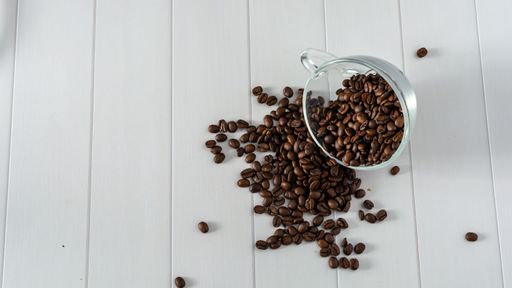 glass cup with coffee beans dropping down table