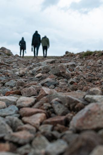 A vertical shot of small stones and a group of hikers going up the surface under a clouded sky