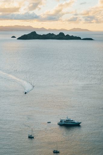 A drone shot of yacht and small boats in the sea of luxury island Caribbean during sunset