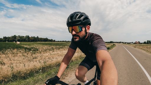 A closeup of a caucasian bicycle rider on the road taking a selfie during the ride.