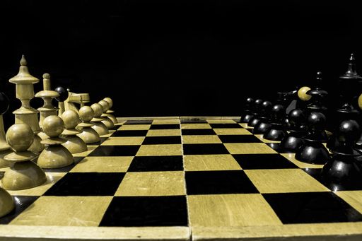 A face-off between black and white chess pieces on black background