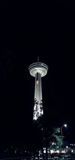 A low angle shot of the Skylon tower standing light on a dark street